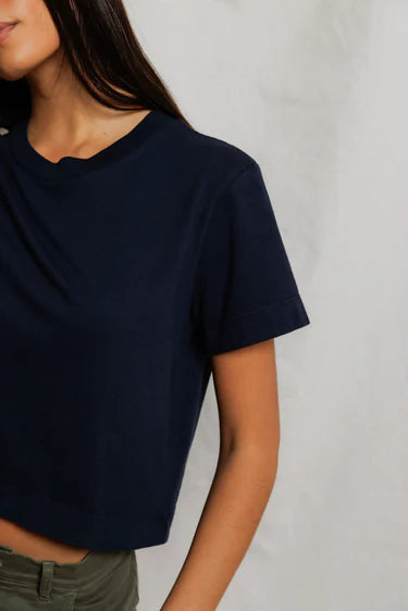 Cher Navy short sleeve tee on a model with green pants and a cream background