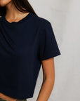 Cher Navy short sleeve tee on a model with green pants and a cream background