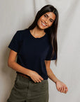 Cher Navy short sleeve tee on a model with green pants and a cream background