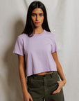 model wearing a purple tee and green pants on a white background