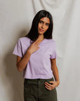 model wearing a purple tee and green pants on a white background