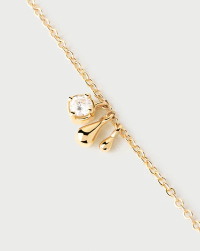 Gold necklace with a bow-shaped pendant on a light gray background detail view