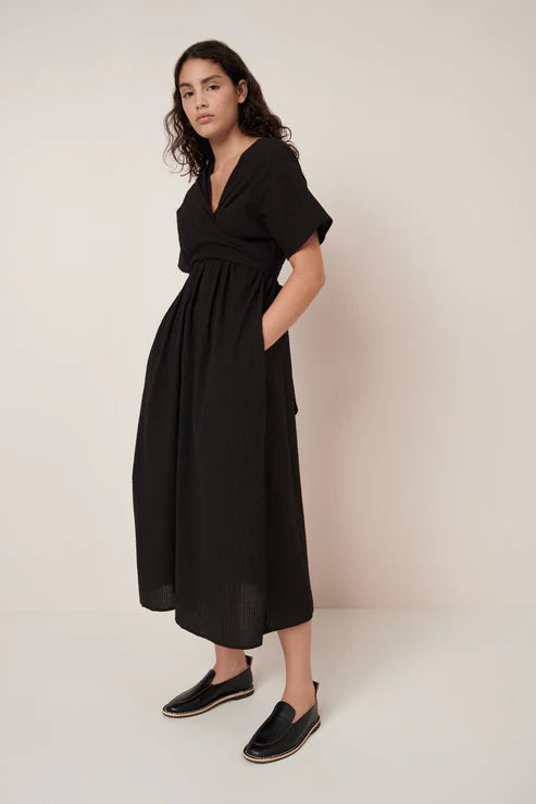 Woman wearing a black dress against a plain background