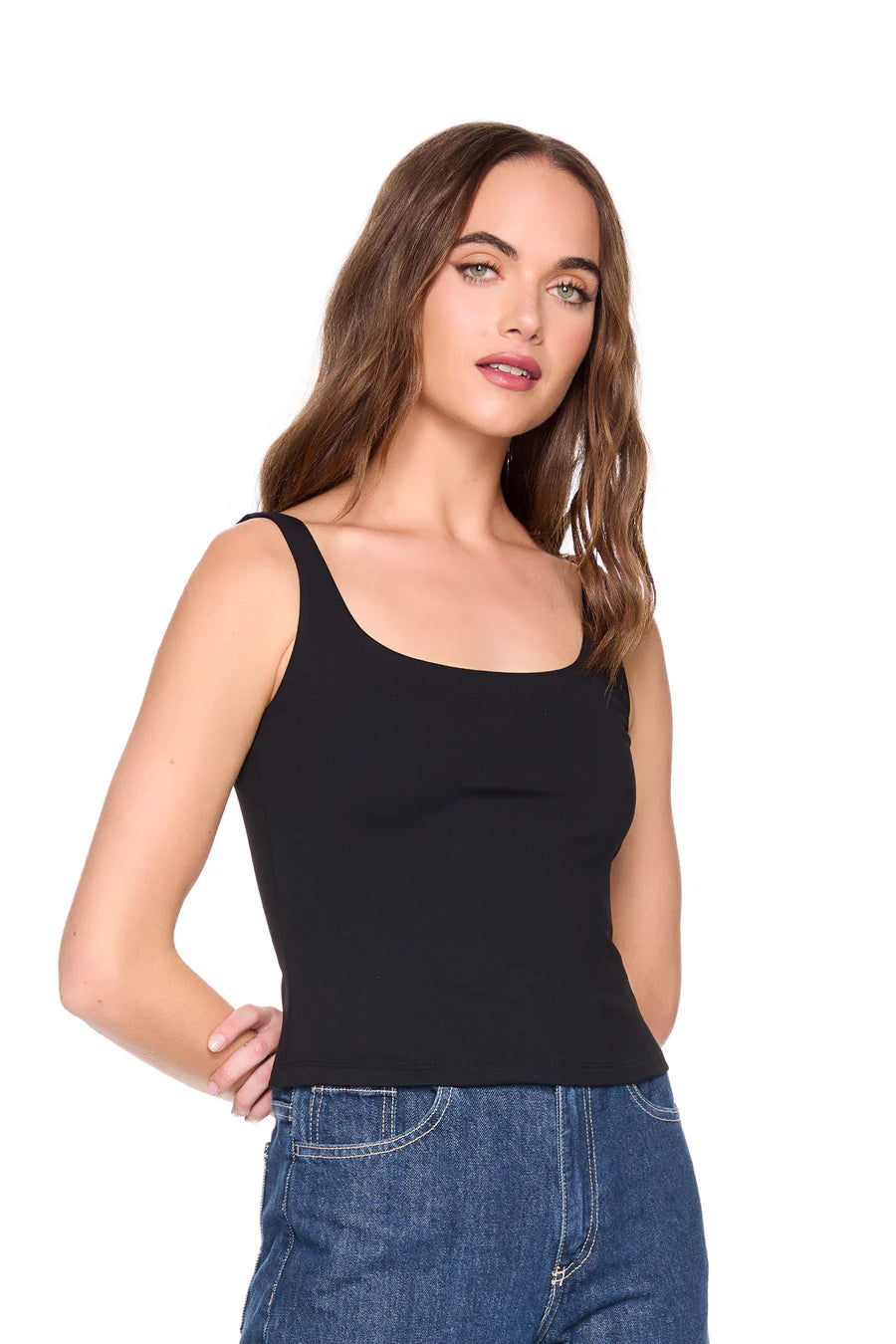 Woman wearing a black tank top and blue jeans on a white background