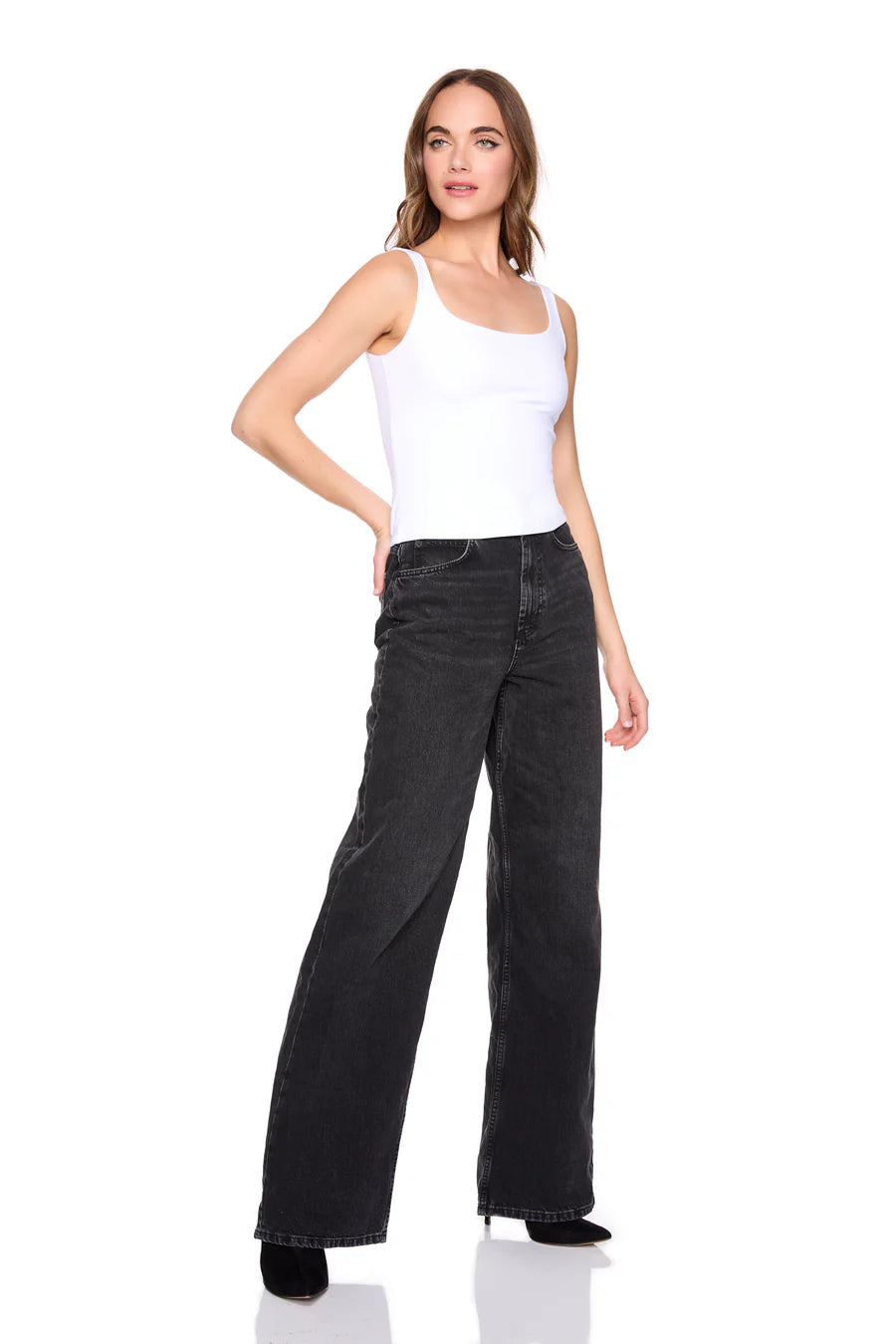 Woman wearing a white tank top and black wide-leg jeans on a white background