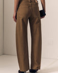 A person shown from the back wearing wide-leg brown pants, a black crop top, and black heels, standing in a plain indoor setting.