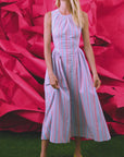 Woman in a striped dress standing against a pink abstract background