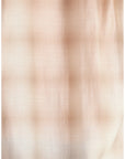 A close-up of a lightweight, semi-sheer fabric with a fine grid or gingham pattern in soft beige and light brown tones.