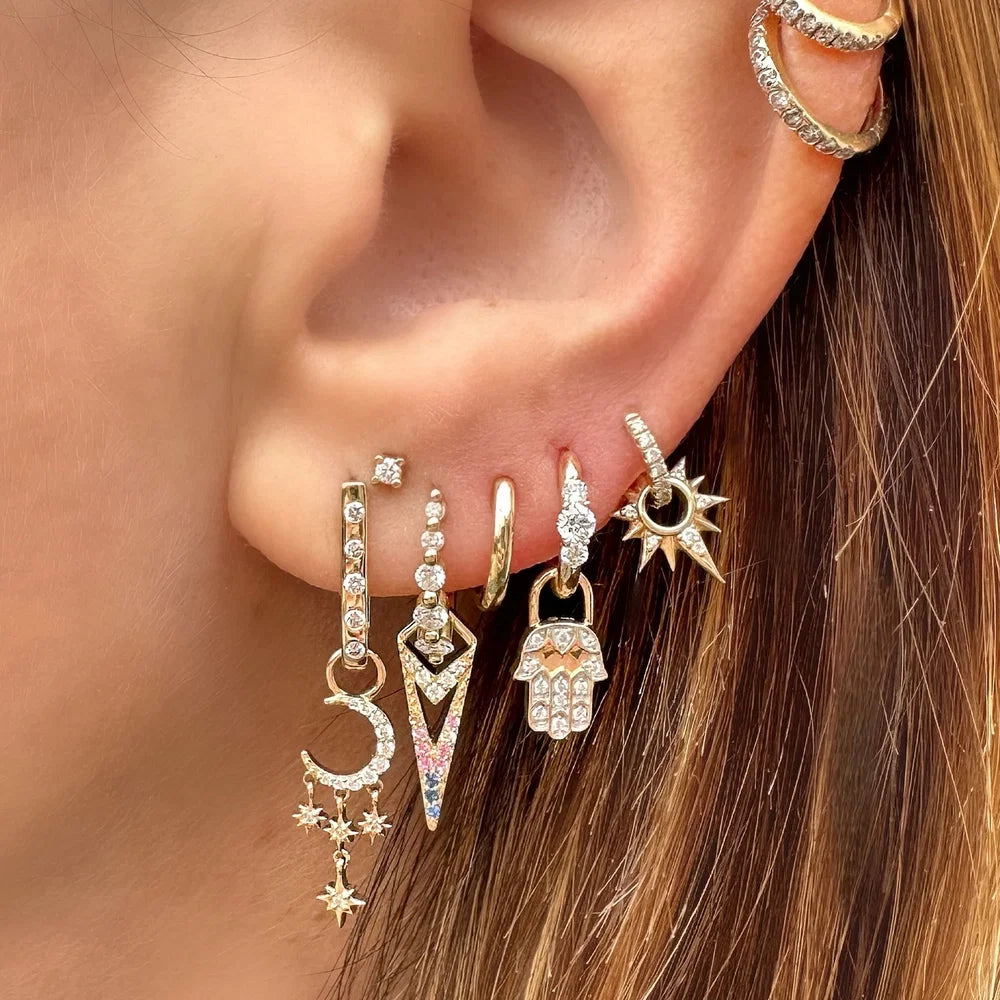 Close-up of an ear with multiple gold earrings featuring various designs.
