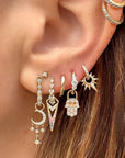 Close-up of an ear with multiple gold earrings featuring various designs.