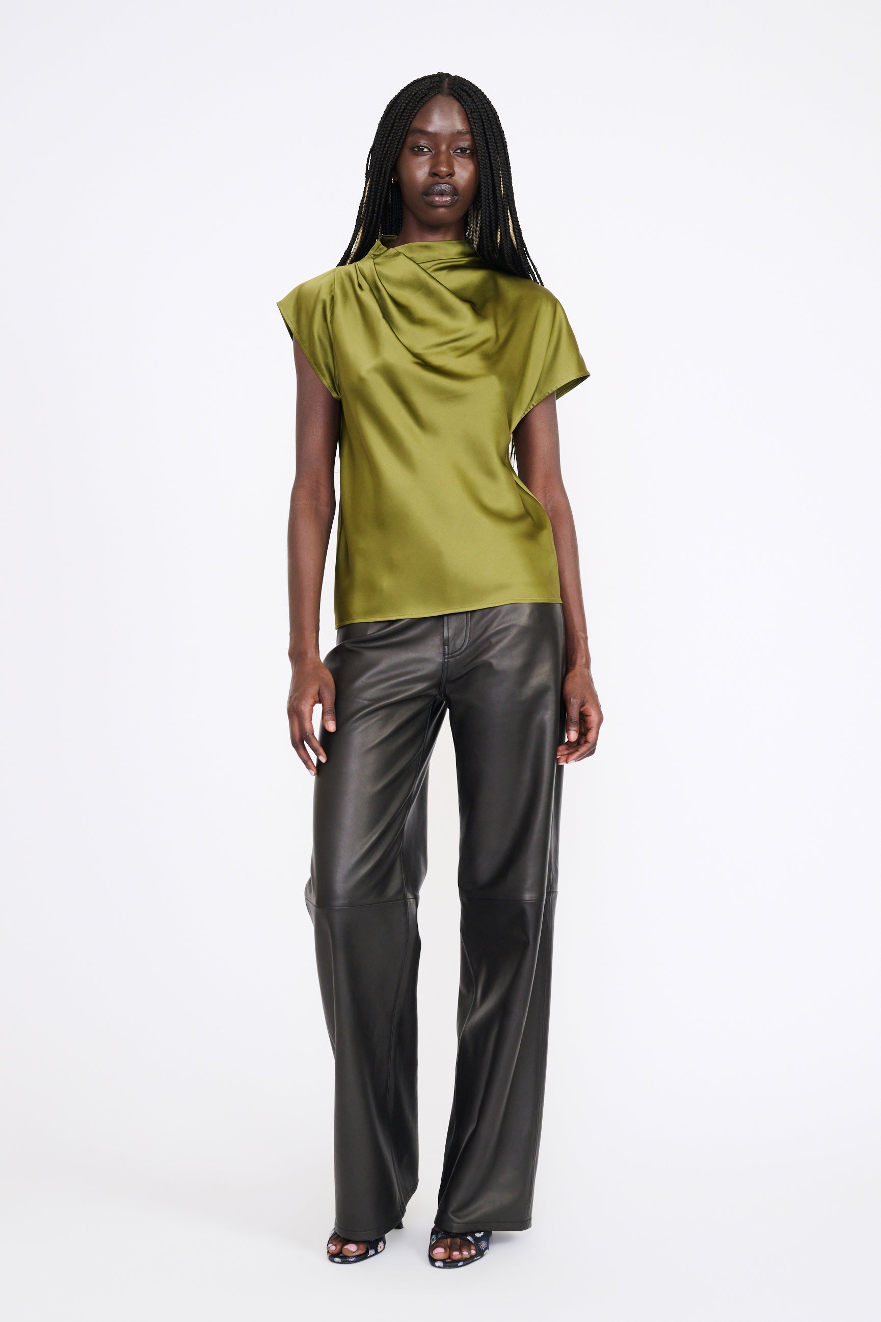 Woman wearing a green top and gray pants on a white background