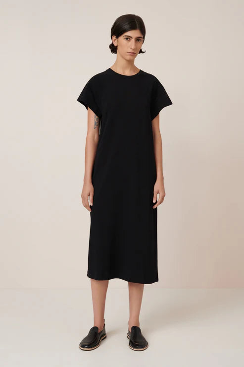 Woman wearing a black dress against a plain background