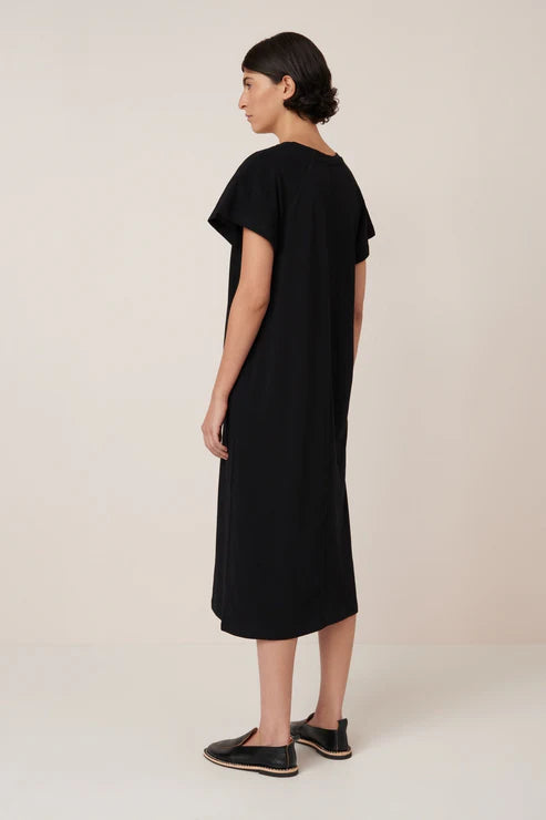 Woman wearing a black dress against a plain background, back