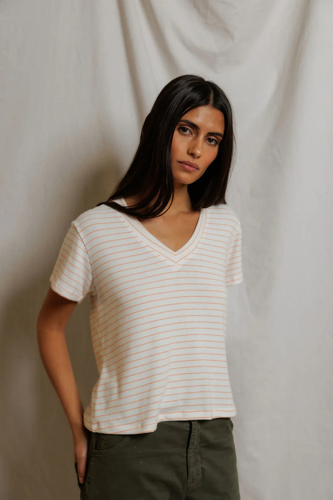 Woman wearing a white striped shirt against a plain background