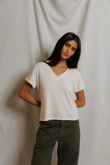 Woman wearing a white striped shirt and green pants against a plain background
