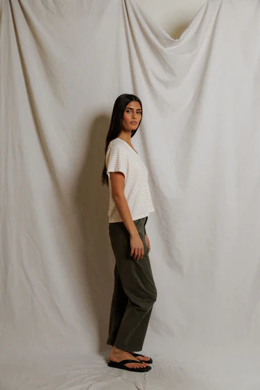 Woman standing against a plain white curtain