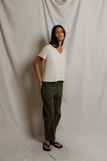 Person wearing a white striped shirt and green pants against a plain background