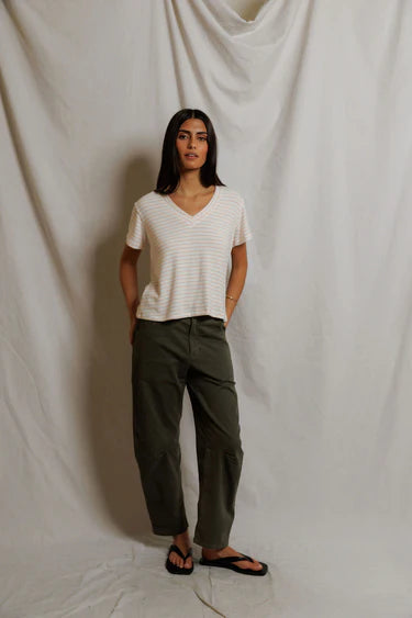 Person wearing a white shirt and green pants against a plain background