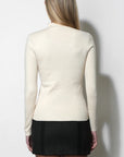 woman wearing a cream long sleeve top with a black mini skirt on a white background, back view
