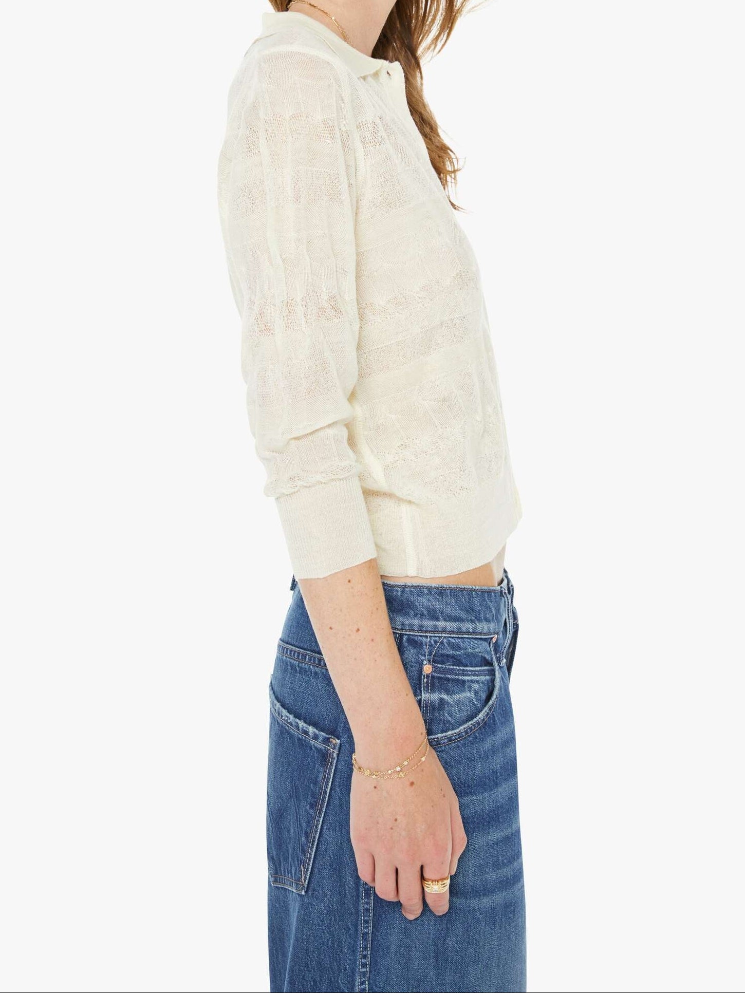 Woman wearing a light-colored blouse and blue jeans on a white background