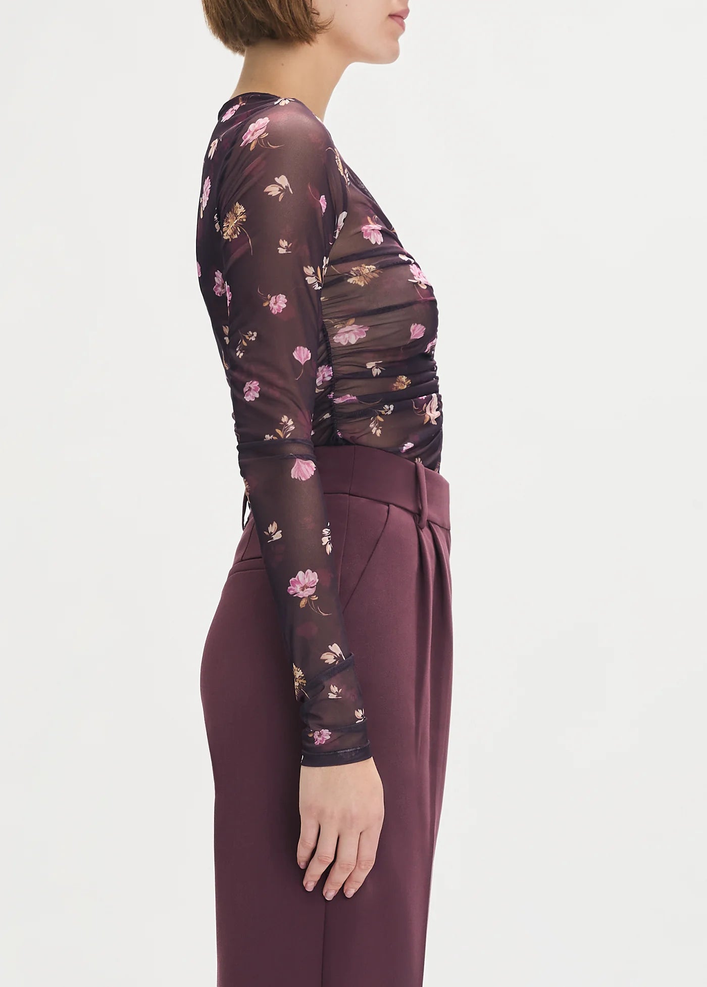 Woman wearing a floral dress with a plain background side view