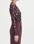 Woman wearing a floral dress with a plain background side view