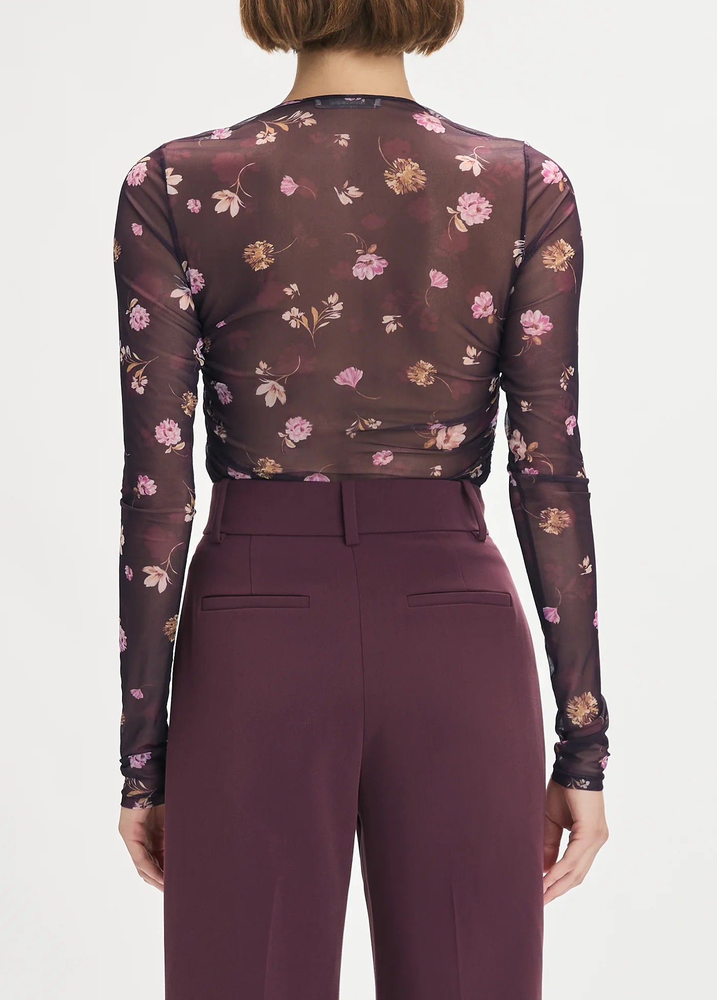 Person wearing a sheer maroon floral top and matching pants on a white background back view