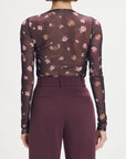 Person wearing a sheer maroon floral top and matching pants on a white background back view