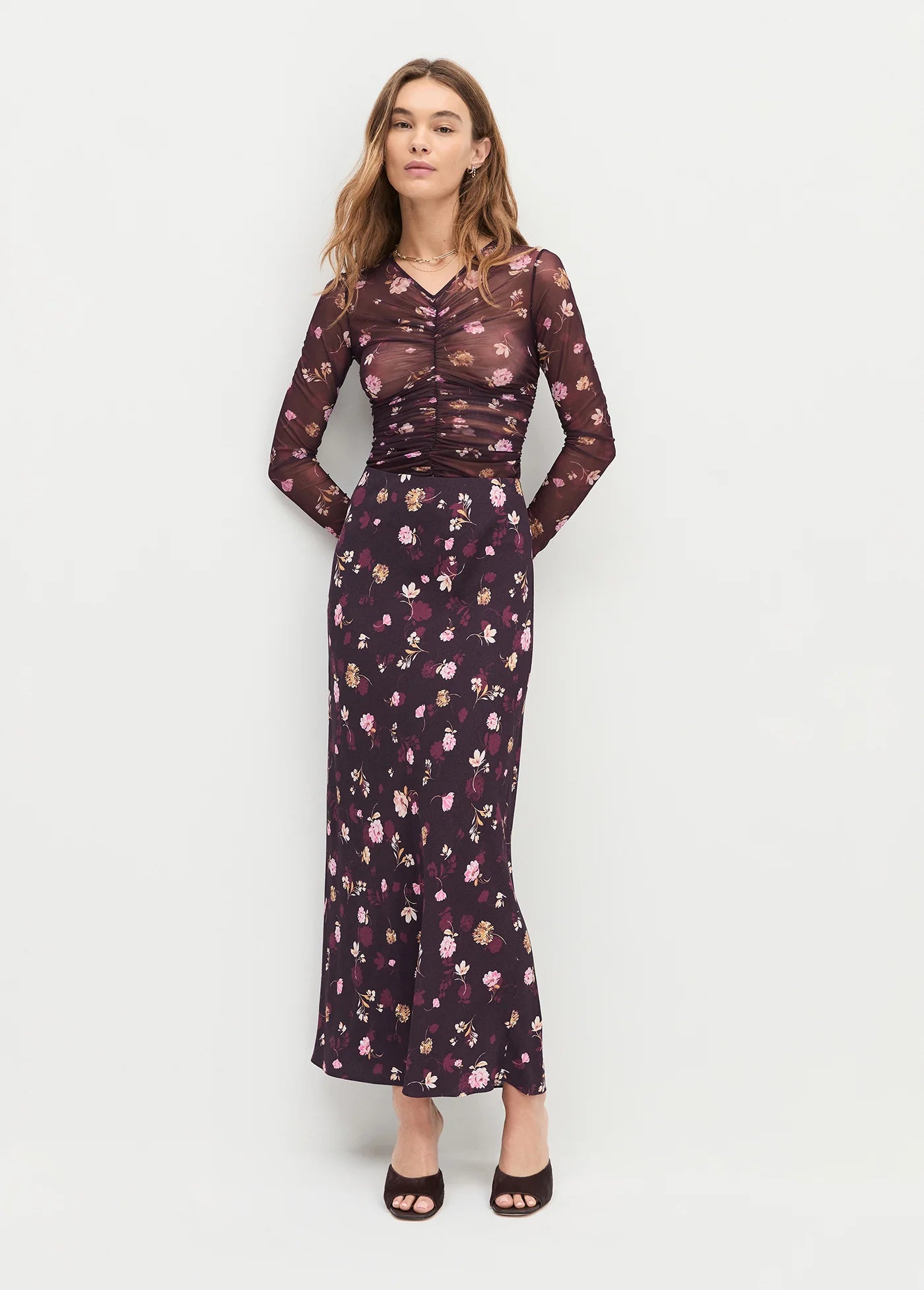 Woman wearing a floral skirt and top on a white background front view