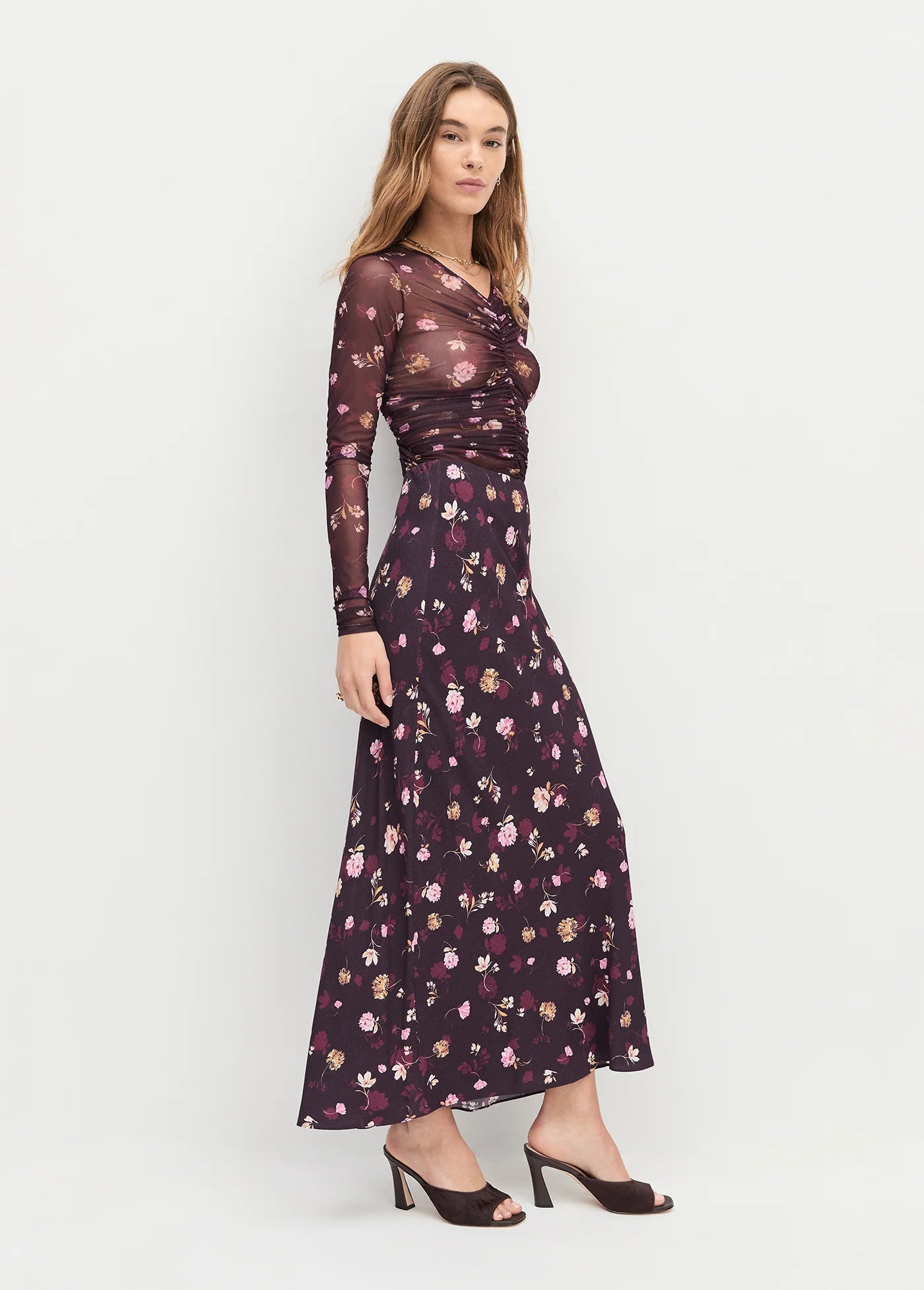 Woman wearing a floral dress on a white background side view