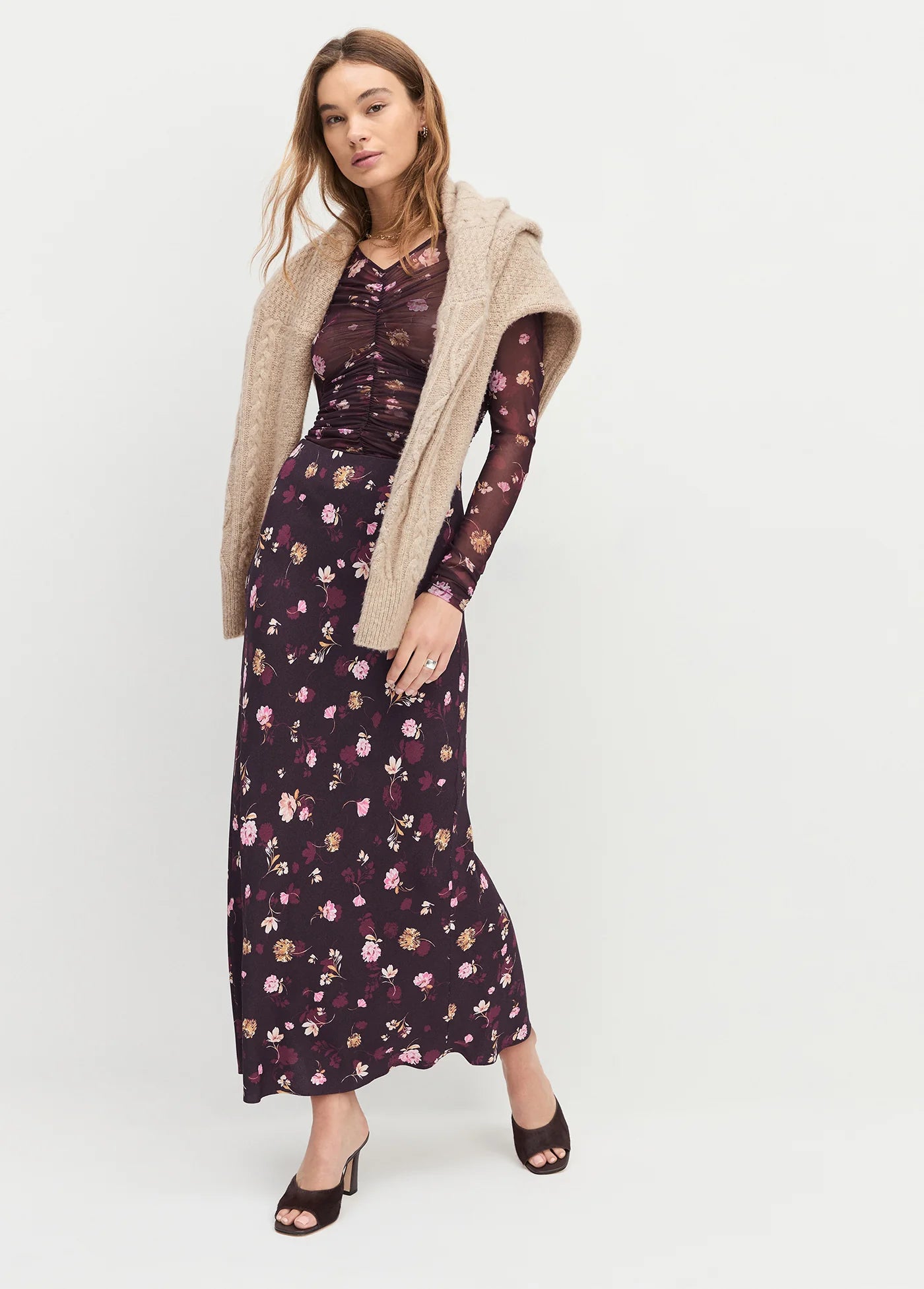 Woman wearing a floral dress with a beige cardigan on a white background front view
