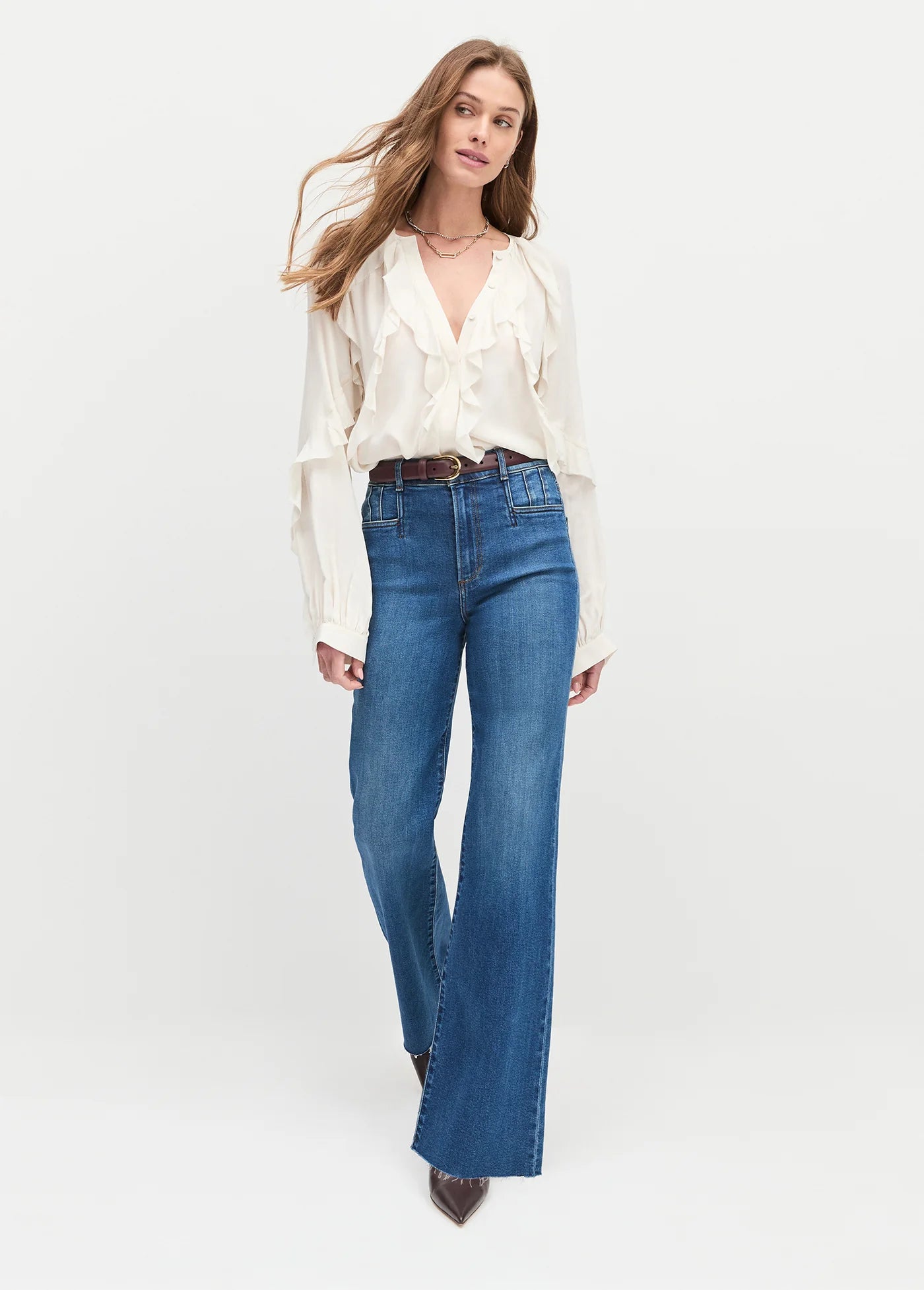 Woman wearing a white blouse and blue jeans on a white background