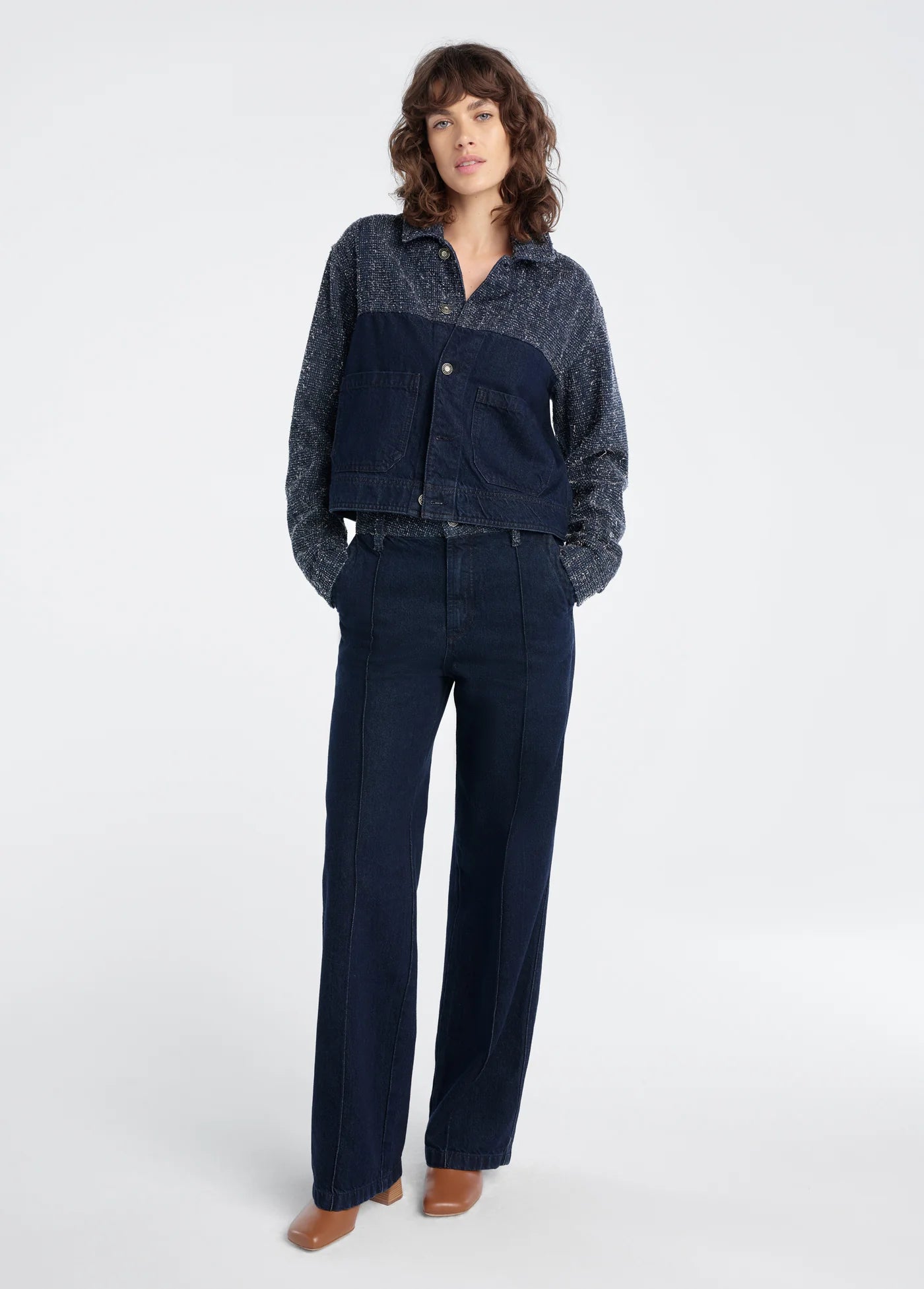 Woman wearing a dark blue denim jacket and pants on a white background