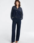 Woman wearing a dark blue denim jacket and pants on a white background