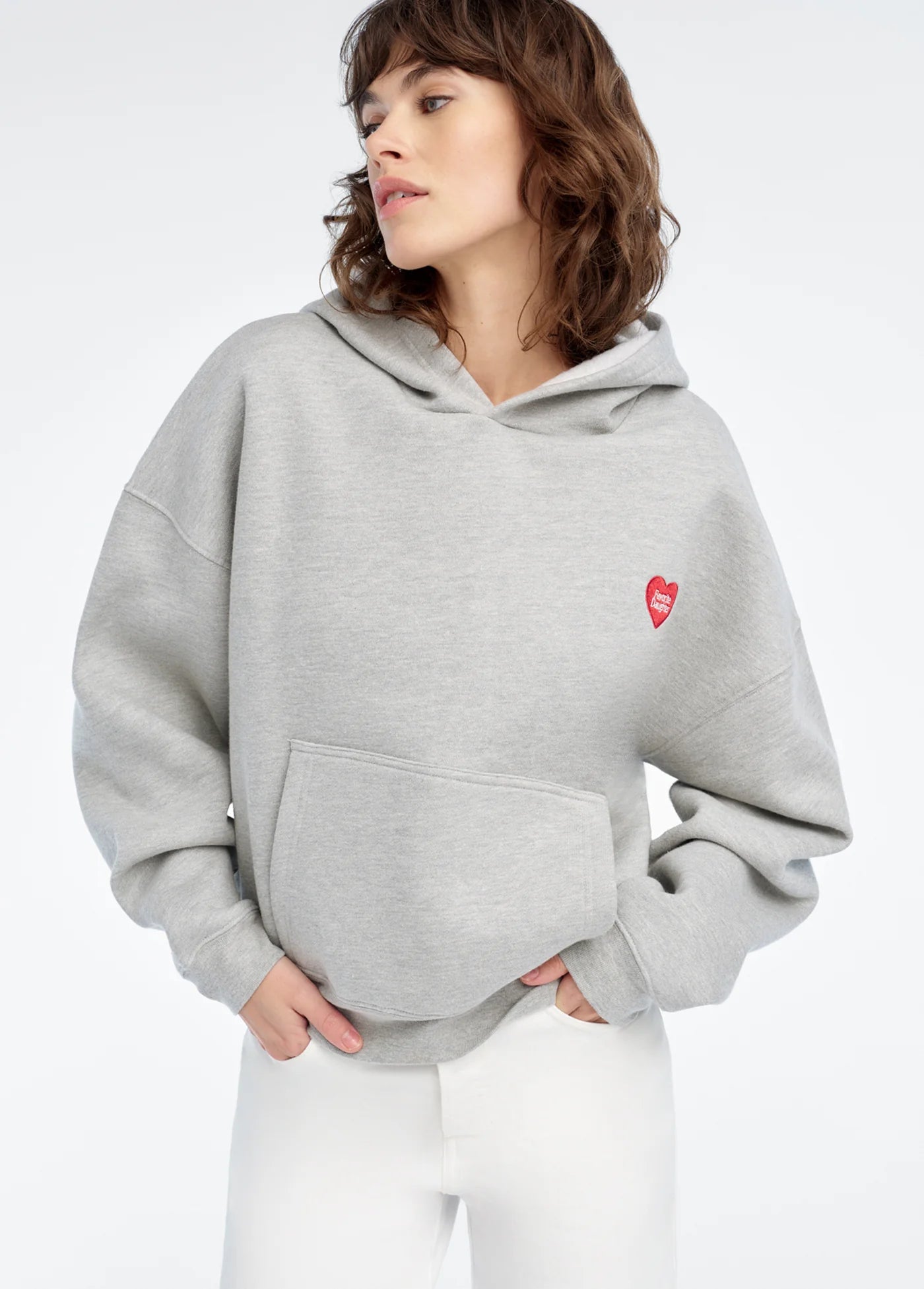 Person wearing a gray hoodie with a red heart logo on a white background