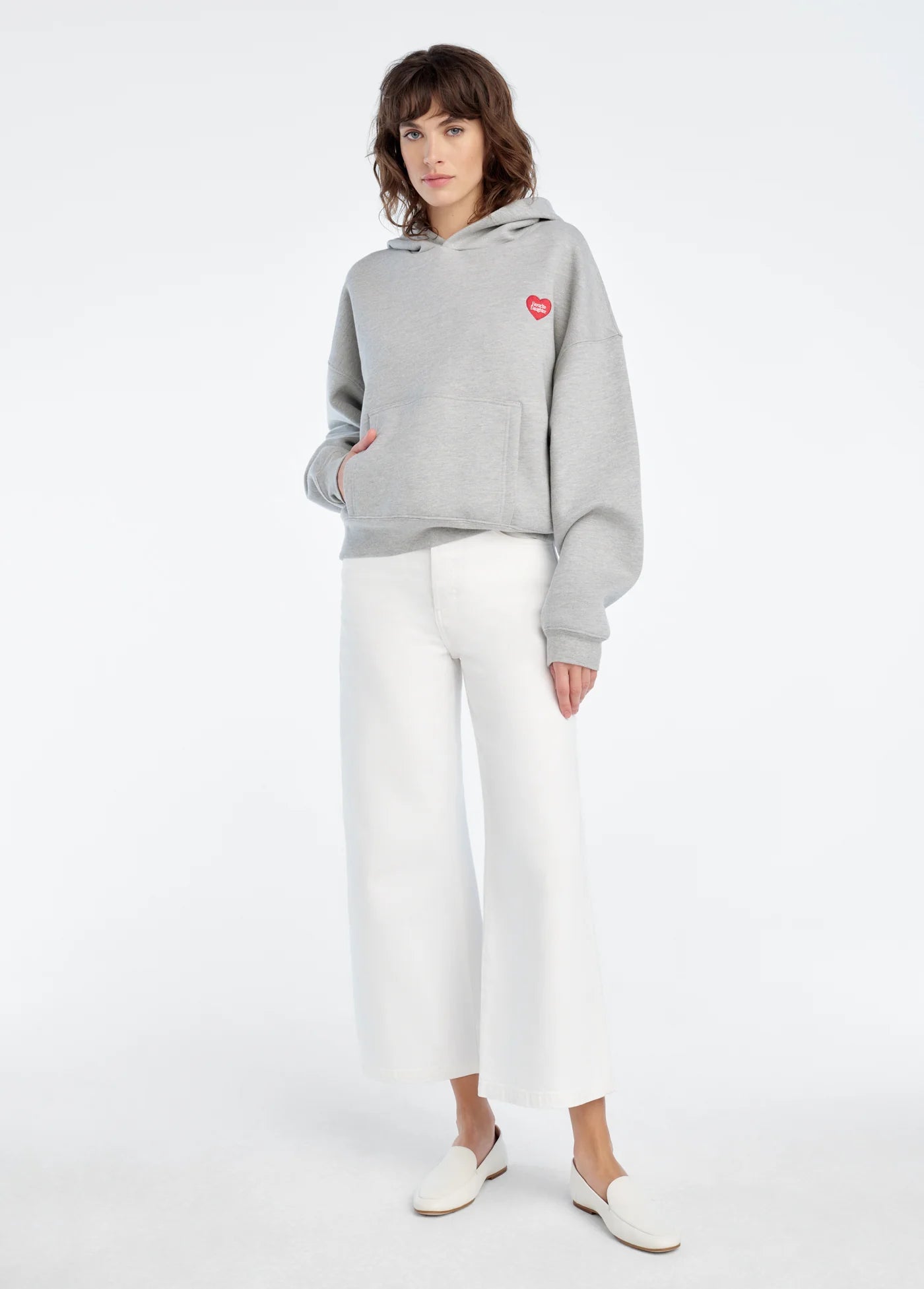 Person wearing a gray hoodie with a red heart on a white background