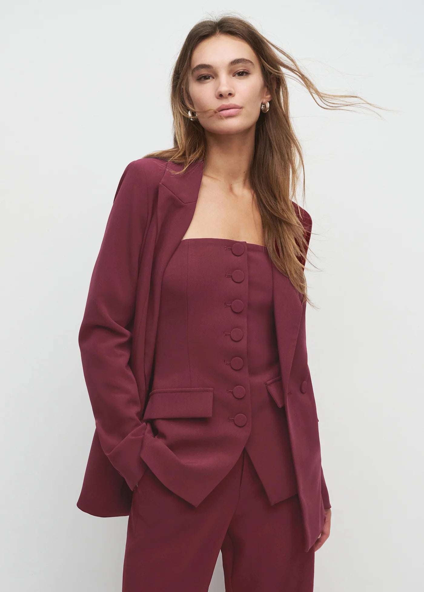 Woman wearing a burgundy suit against a white background