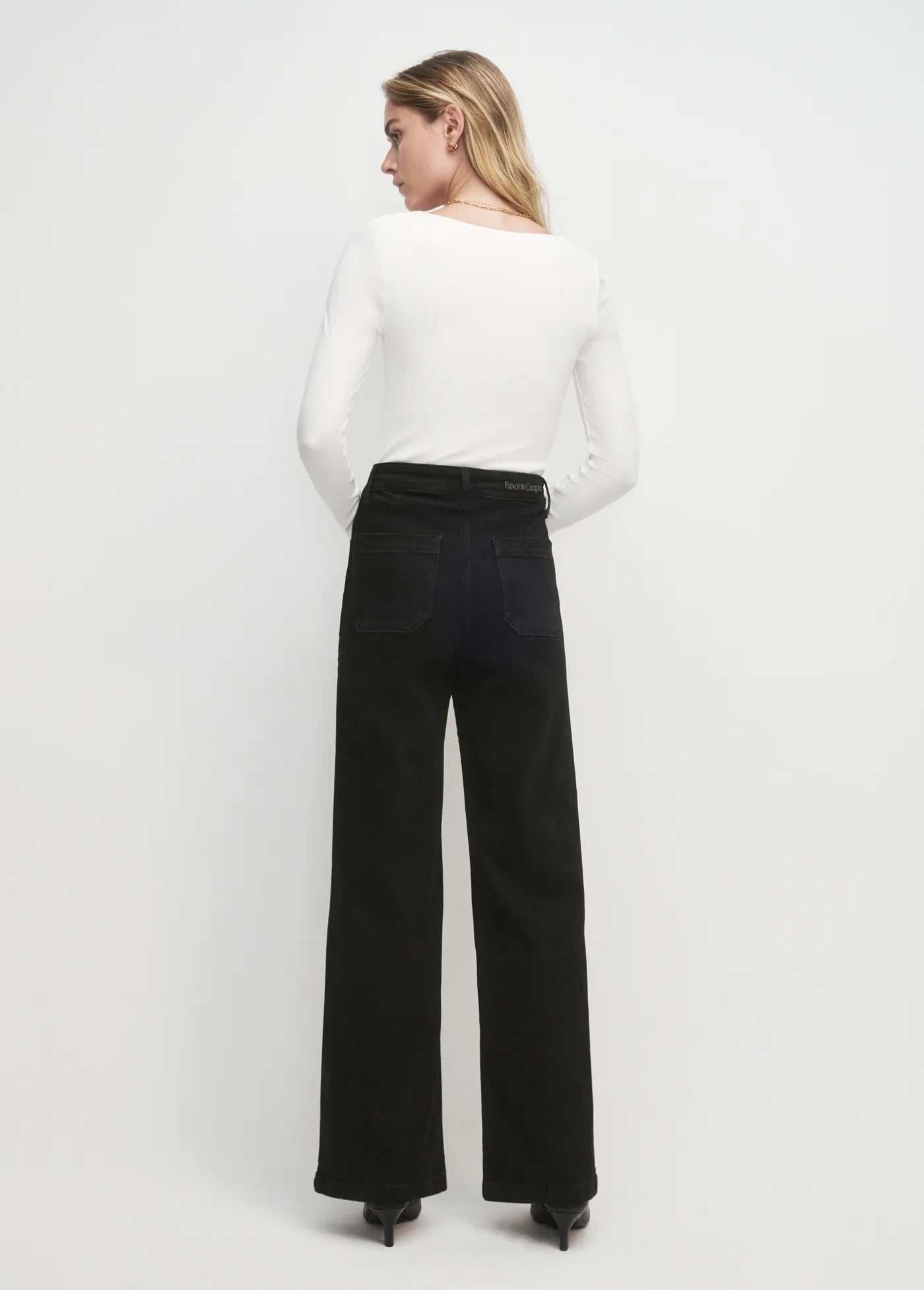Woman wearing a white top and black pants on a white background