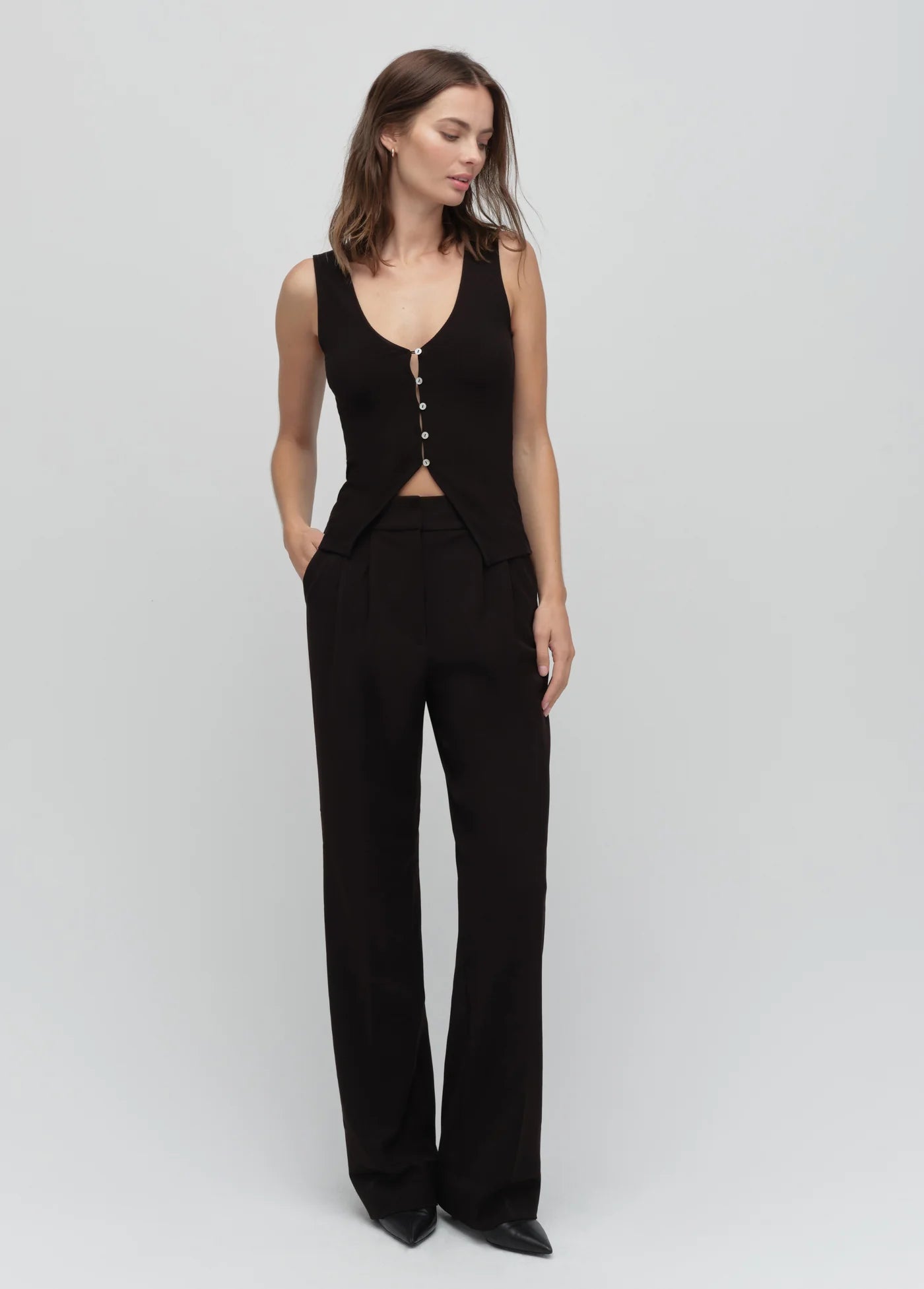 Woman wearing a black sleeveless top and pants on a white background