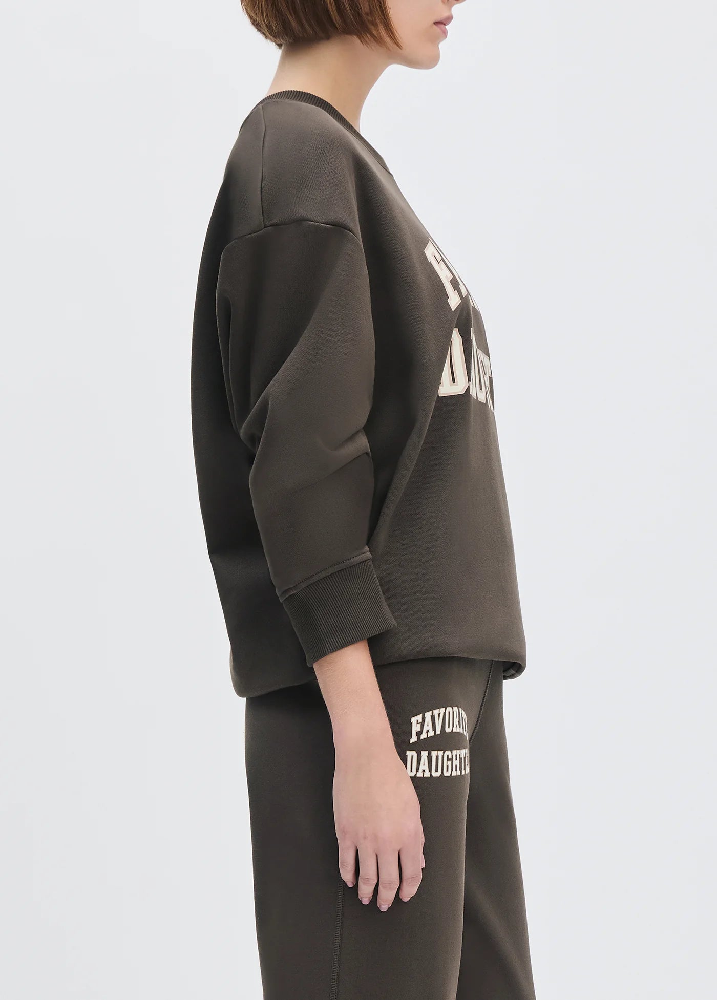 model wearing collegiate sweatshirt with brown pants with a white background