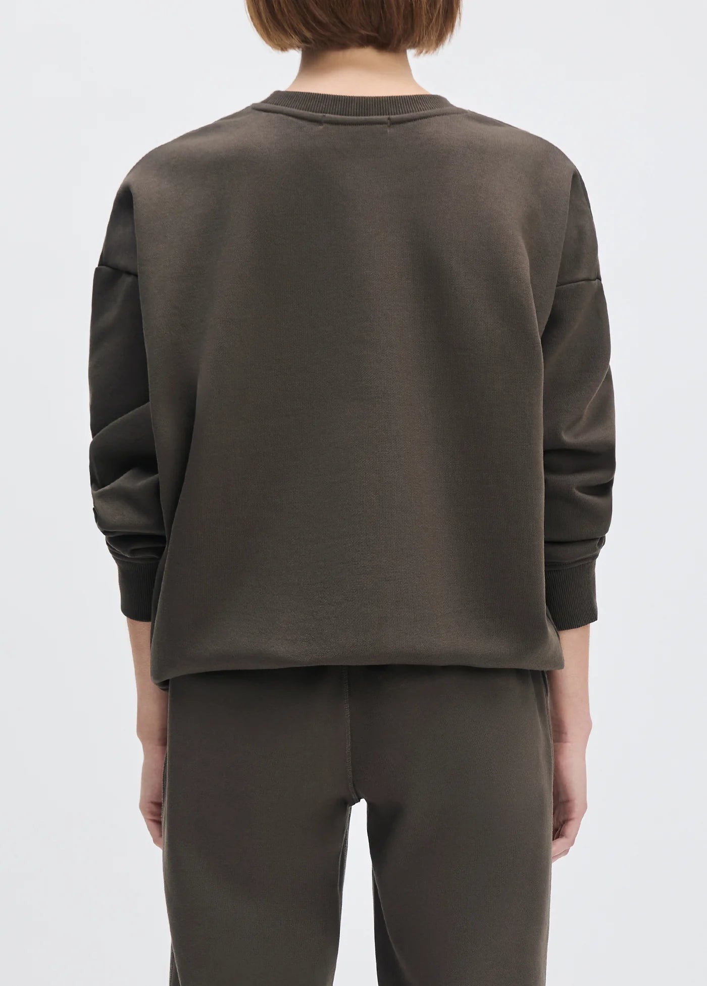 model wearing collegiate sweatshirt with brown pants with a white background