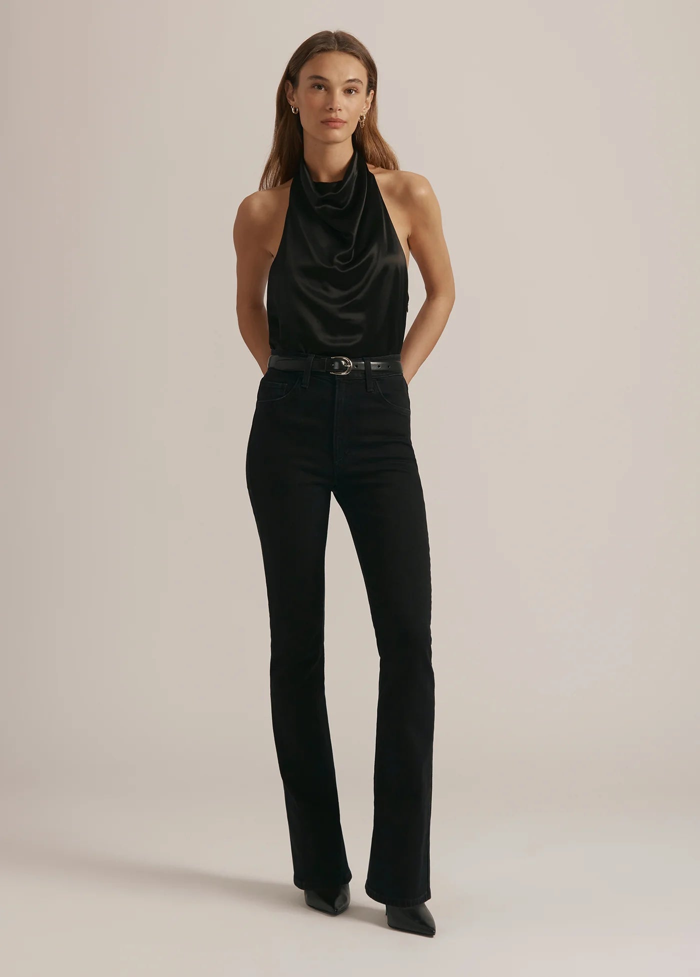 Woman wearing a black sleeveless top and black pants against a beige background