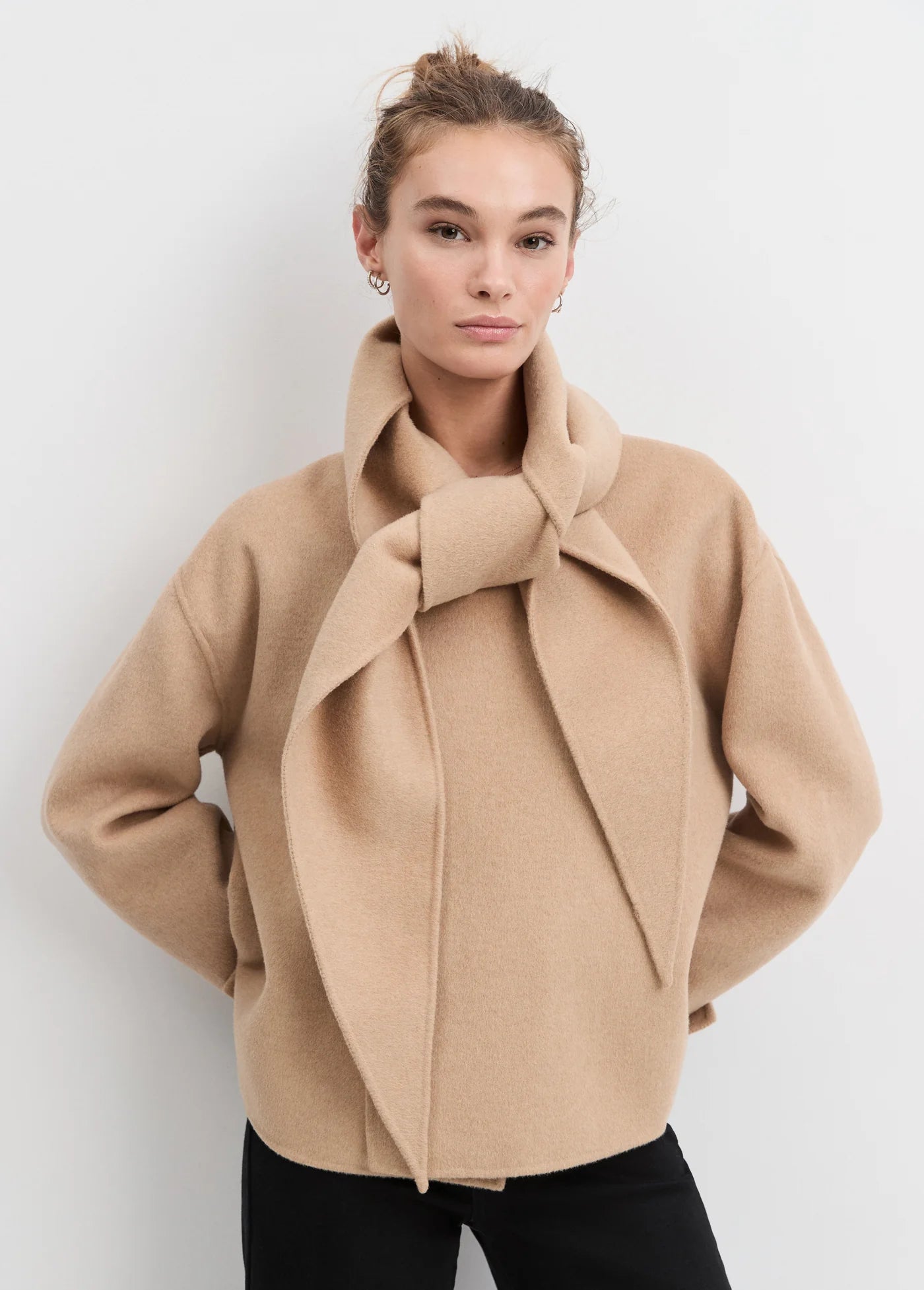 Woman wearing a beige coat against a white background