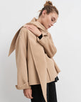 Woman wearing a beige coat against a white background