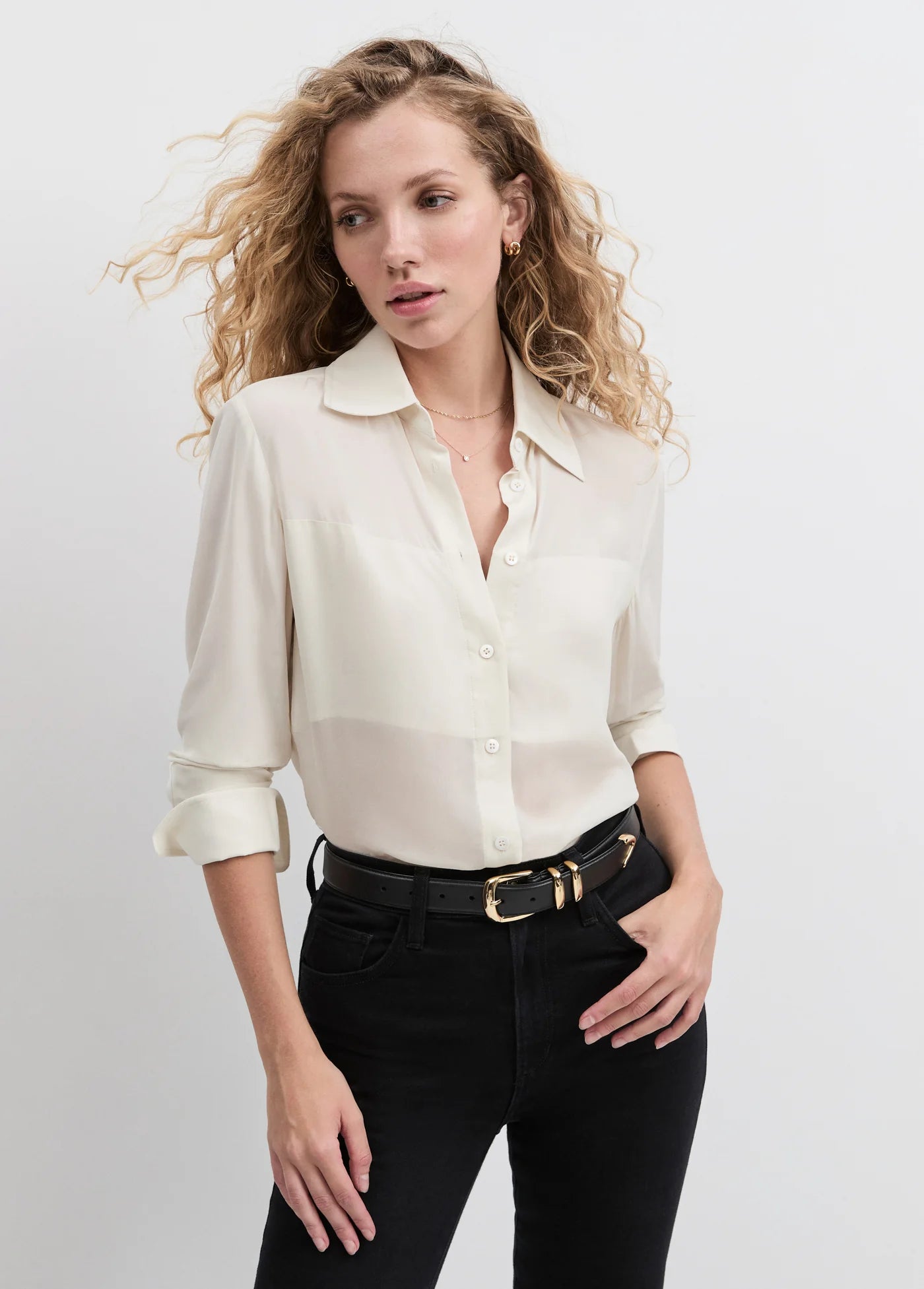 Woman wearing a white blouse and black pants on a plain background