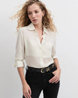 Woman wearing a white blouse and black pants on a plain background