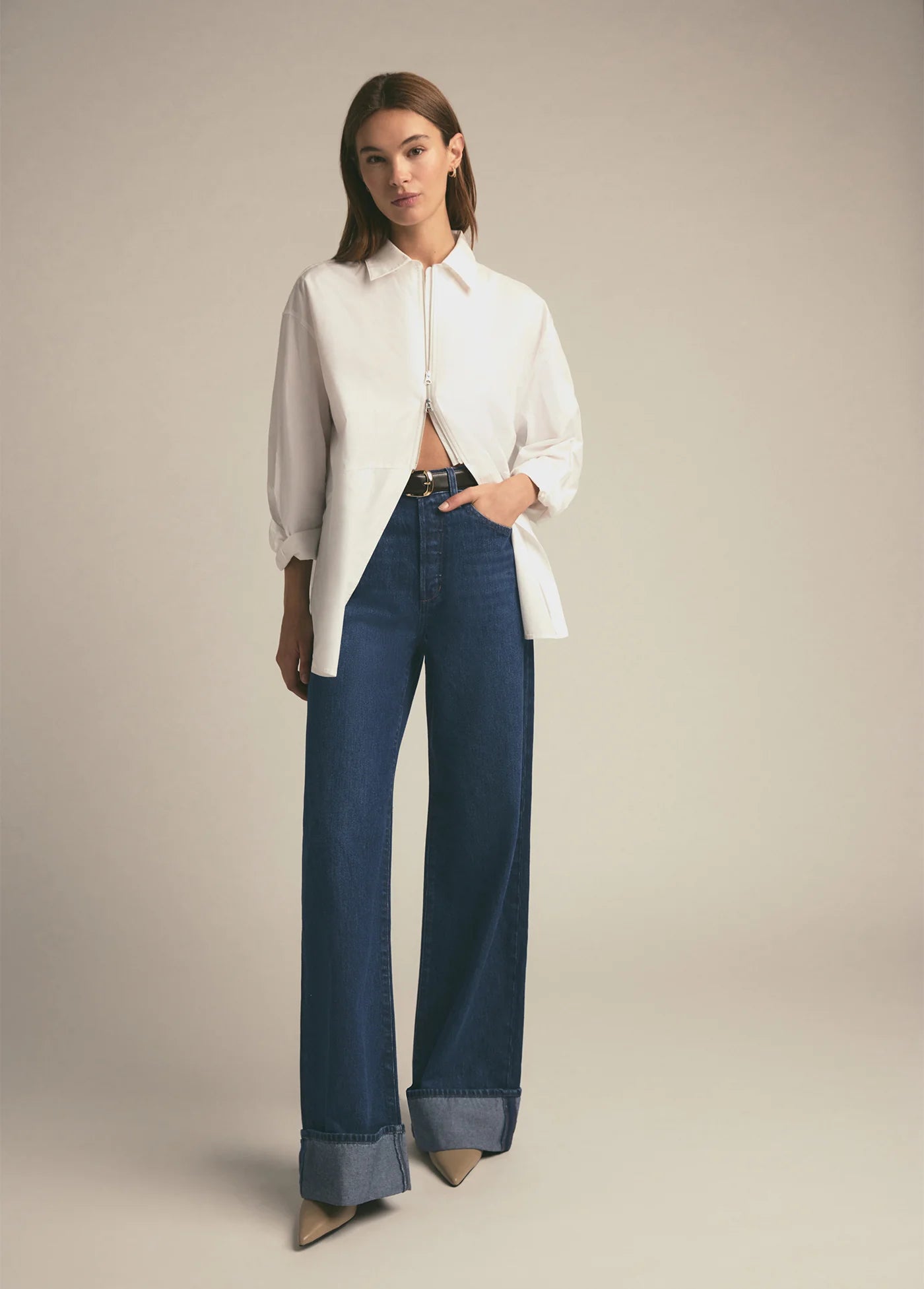 Woman wearing a white blouse and blue jeans on a plain background