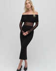 Woman wearing a black off-shoulder dress with sheer mesh panels on a white background