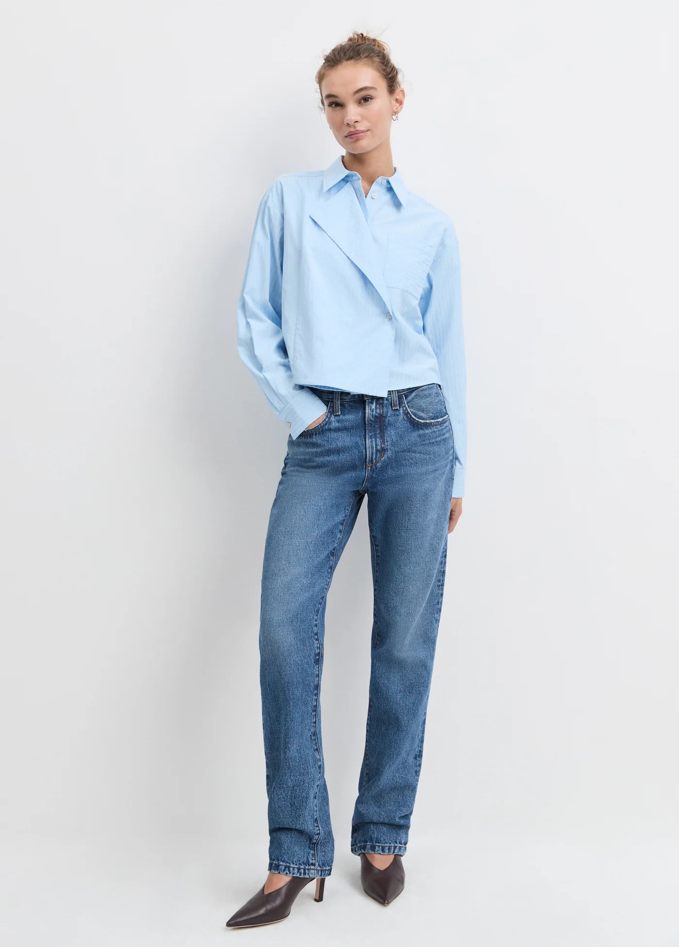 Model wearing the light blue stripe jenni top with jean and heels on a white background