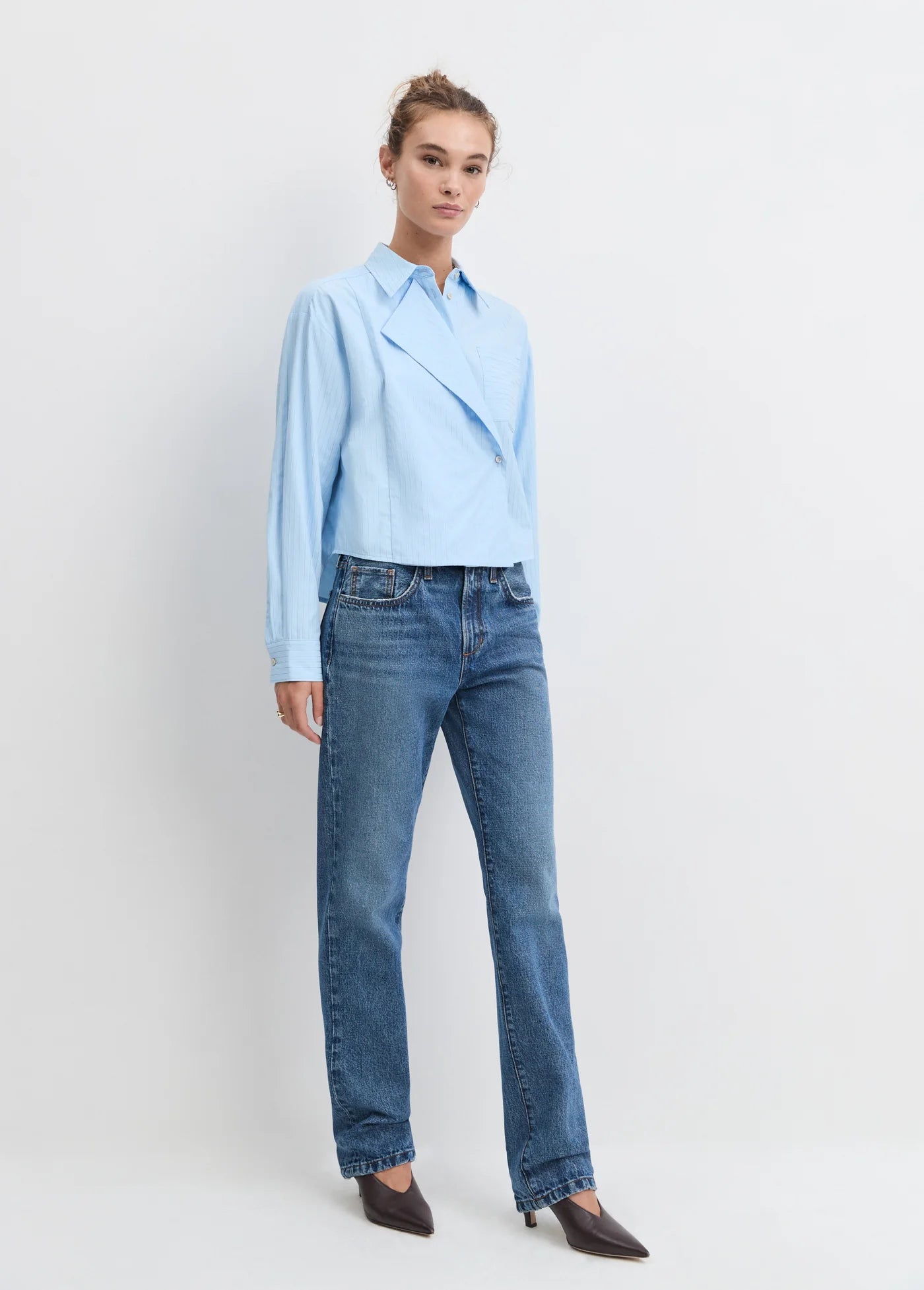 Model wearing the light blue stripe jenni top with jean and heels on a white background
